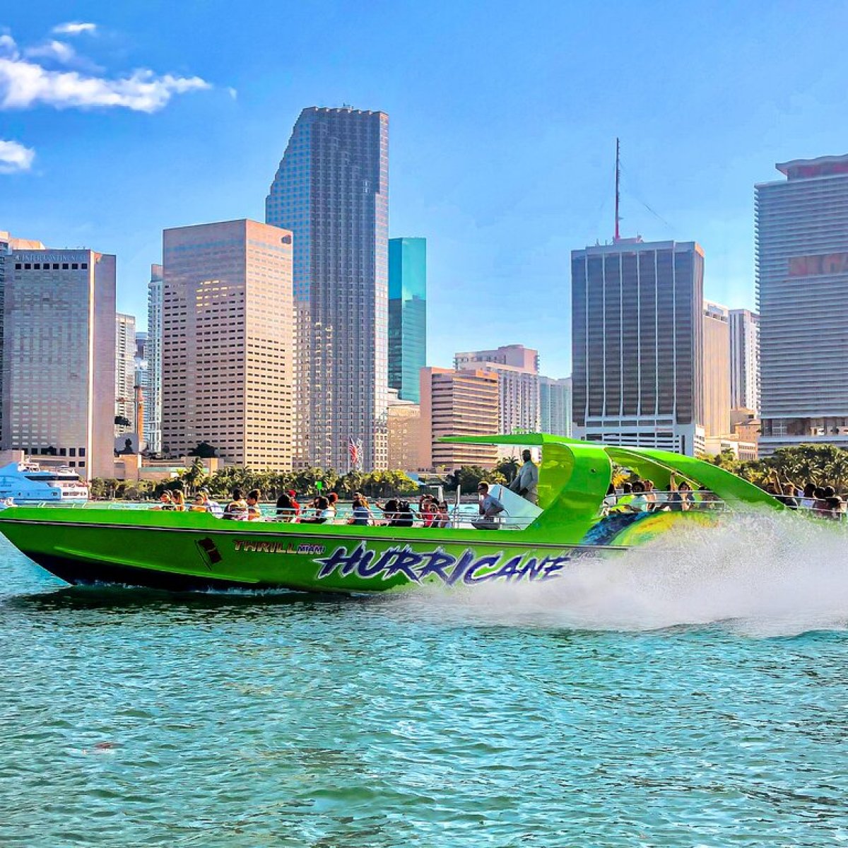 a green boat on a body of water with a city in the background