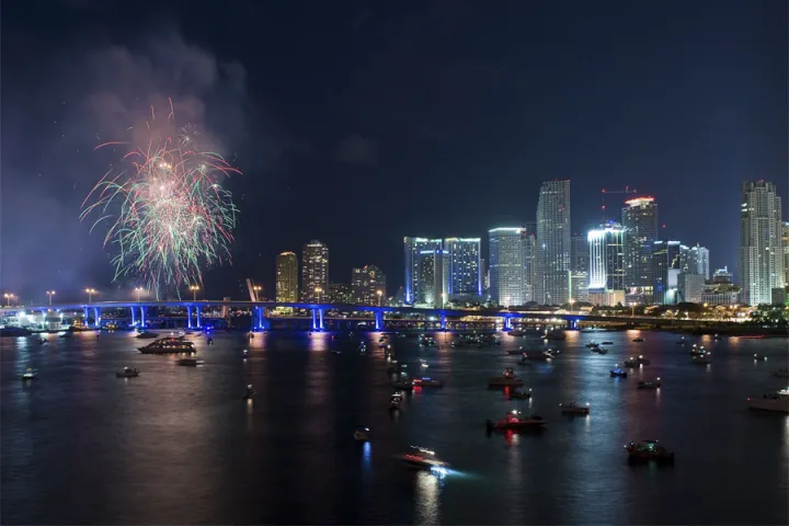 a group of fireworks in the water with a city in the background