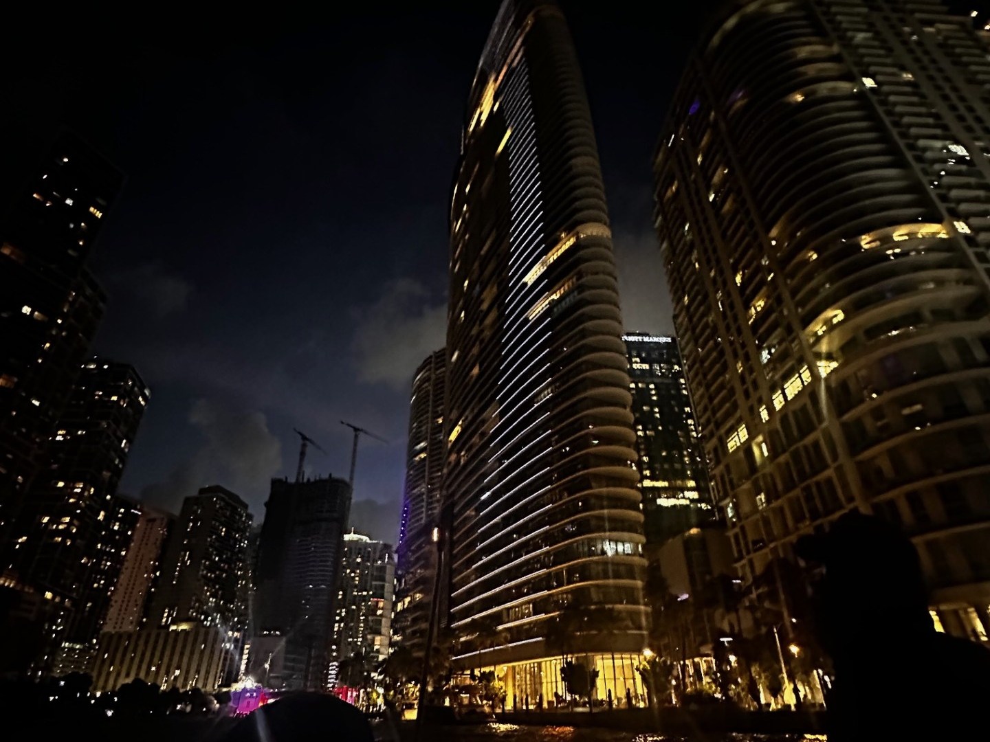 Skyscrapers with illuminated windows at night, silhouetted figures in foreground.