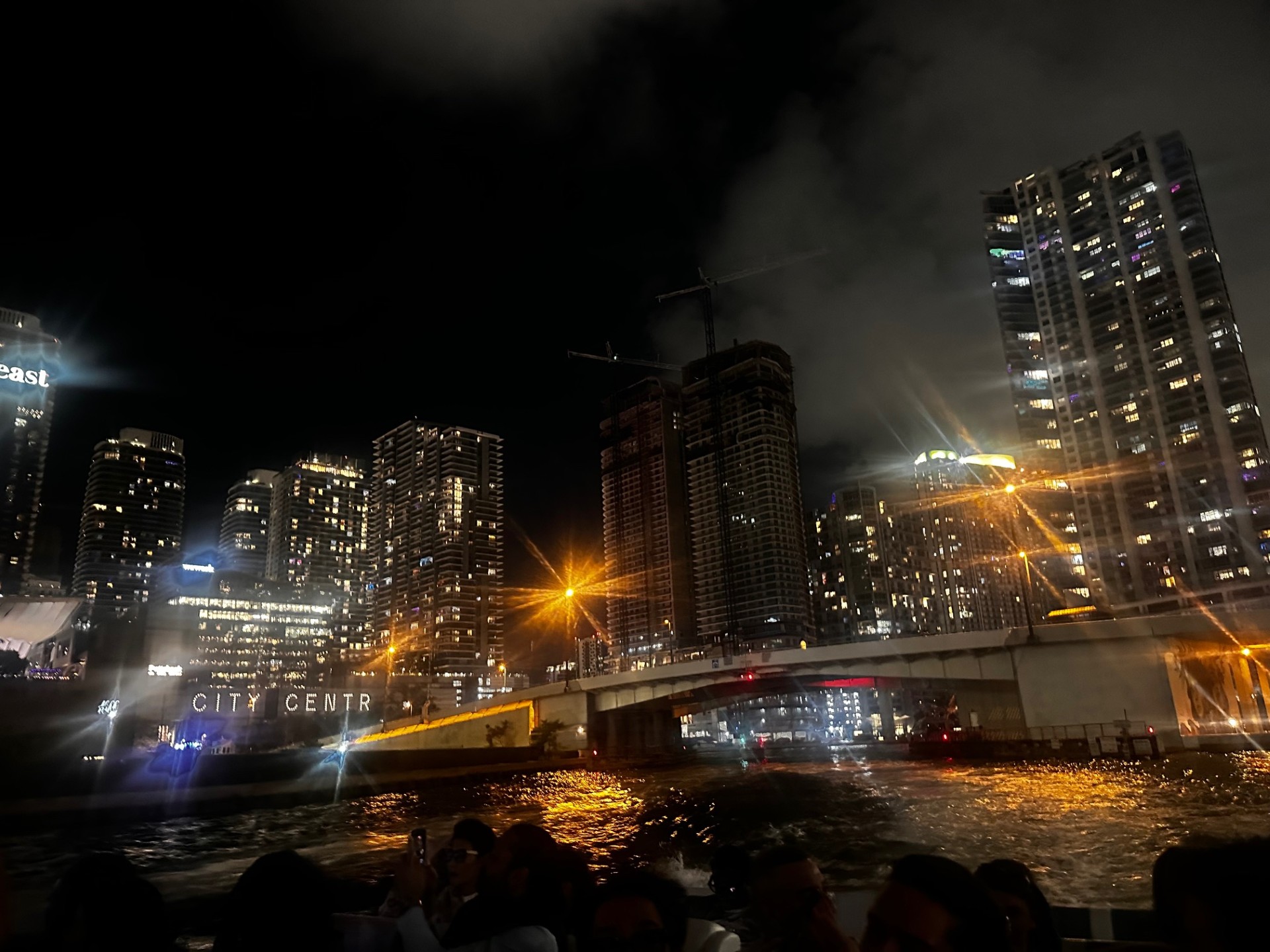 Night cityscape with lit skyscrapers and bridge over water.